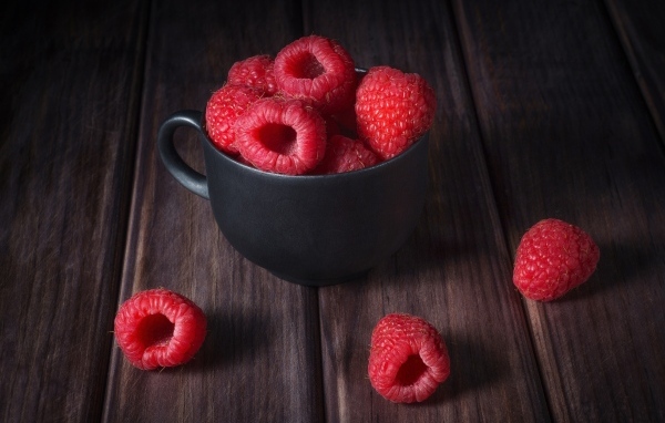 Черная чашка с красными ягодами малины