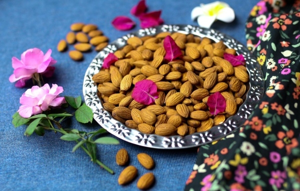 Вкусные миндальные орехи на тарелке с цветами