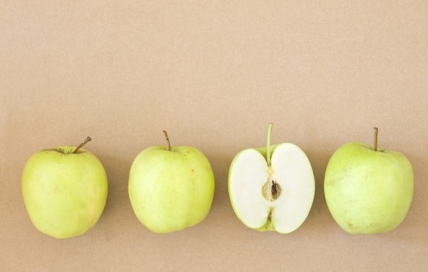 Четыре зеленых яблока на бежевом фоне 
