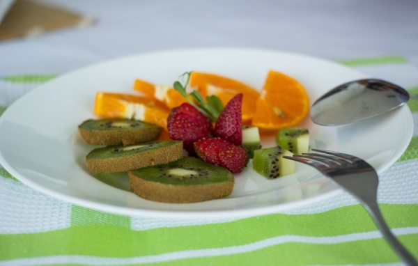 Свежие нарезанные фрукты на тарелке с вилкой