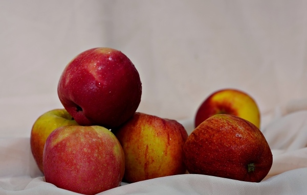Много красных яблок с белой тканью 
