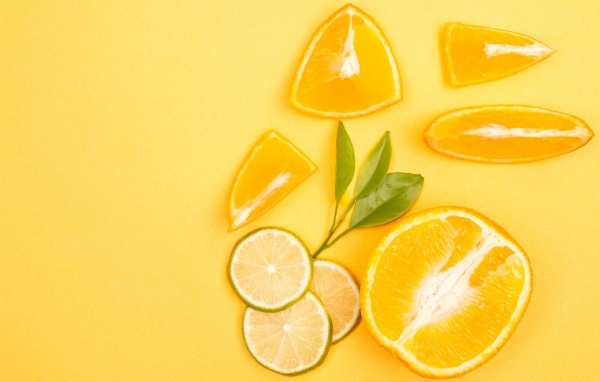 Нарезанные плоды апельсина и лайма на желтом фоне