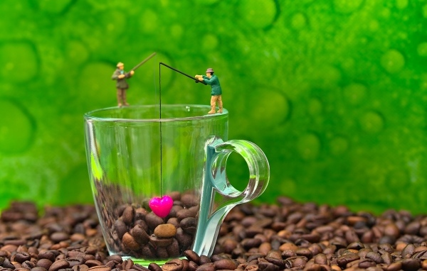 Две фигурки на стеклянной чашкой с кофейными зернами