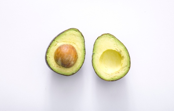 Две половинки зеленого авокадо на сером фоне