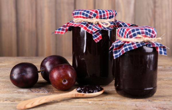 Две банки джема на столе со сливами