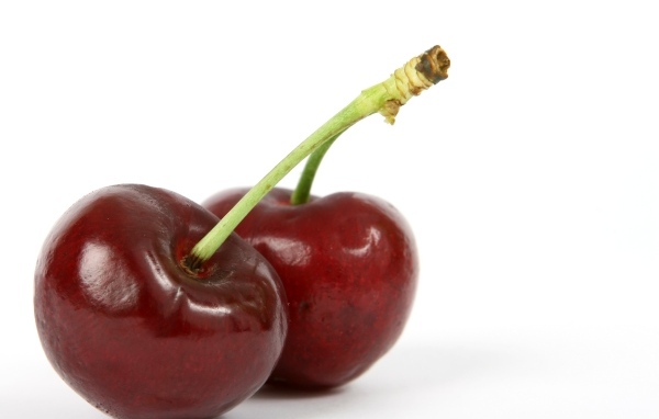 Две красные ягоды черешни на белом фоне