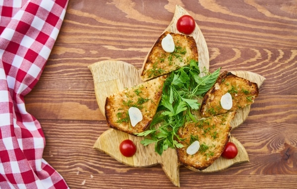 Жареный хлеб на доске с зеленью и помидорами