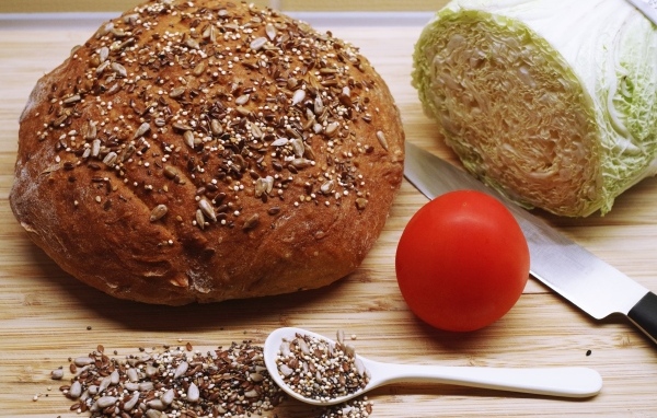 Буханка хлеба на столе с капустой и помидором