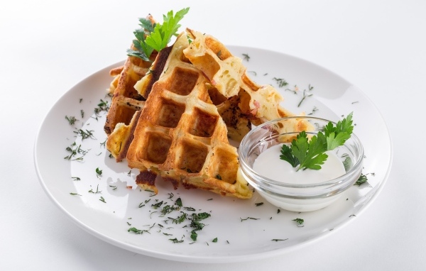 Вафли с соусом и зеленью на тарелке