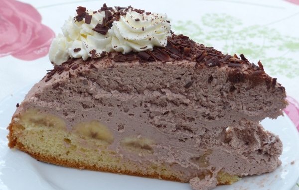 Кусок аппетитного торта с кремом на белой тарелке