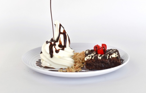 Пирожное со взбитыми сливками на тарелке на белом фоне