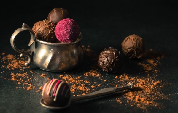 Шоколадные конфеты с железной чашкой на черном фоне