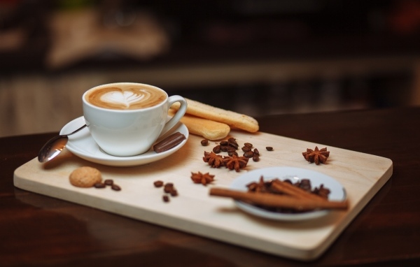 Чашка кофе на доске с печеньем и специями