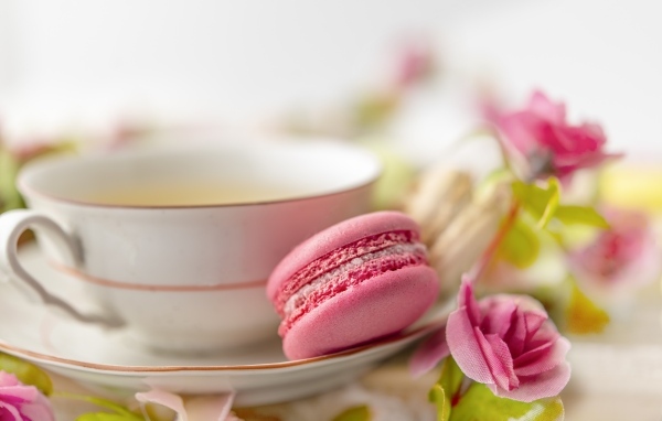 Чашка чая с десертом макарун и цветами розы