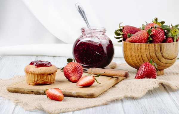 Кекс со свежей клубникой и джемом на столе