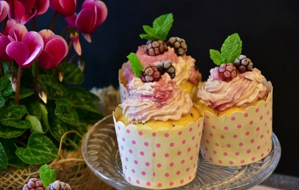 Капкейки с кремом и ягодами черники на столе с цветком