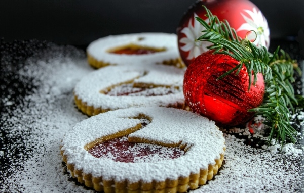 Вкусное сладкое печенье в сахарной пудре на столе с елочными игрушками