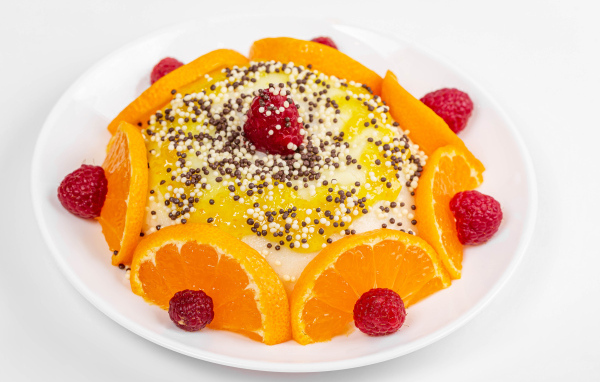 Десерт с кусочками апельсина и ягодами малины на белом фоне