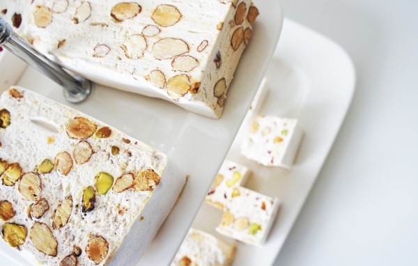 Нуга с орехами на белой тарелке