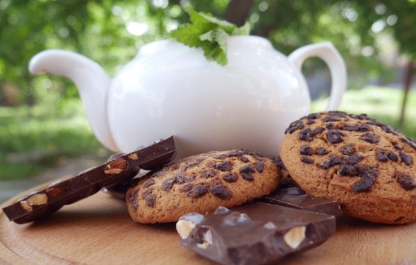 Чайник на столе с печеньем и шоколадом