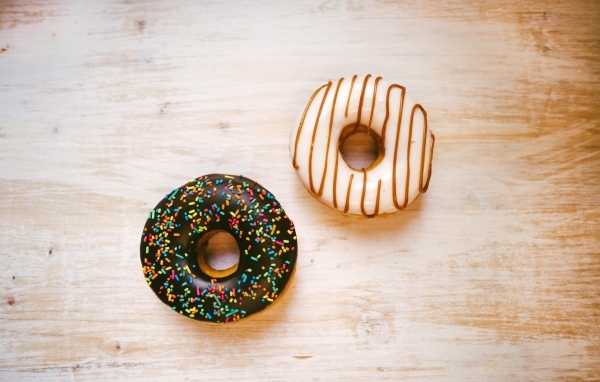 Два пончика в глазури на деревянном столе