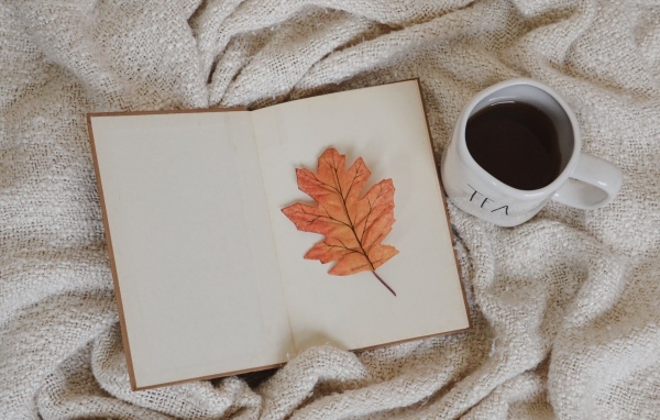 Книга, желтый лист и чашка кофе с пледом