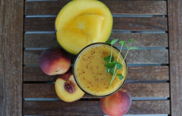 Коктейль с веточкой мяты на столе с фруктами