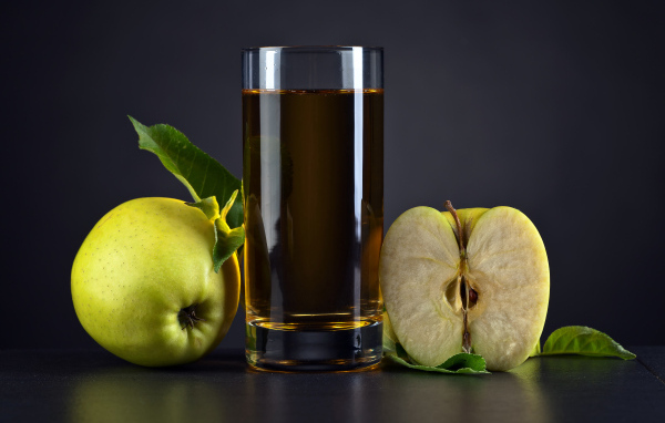 Стакан сока с зелеными яблоками на сером столе