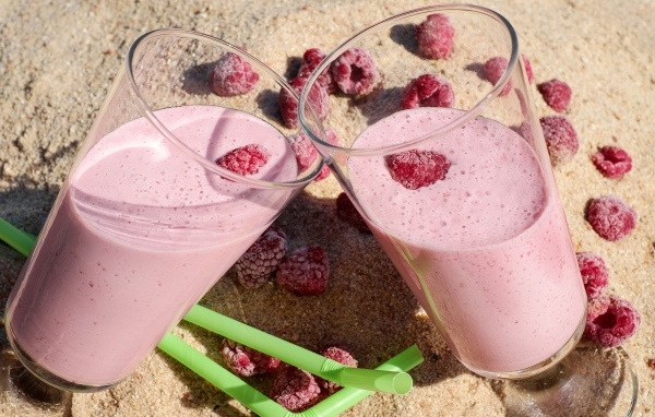 Два стакана ягодного смузи с малиной на песке 