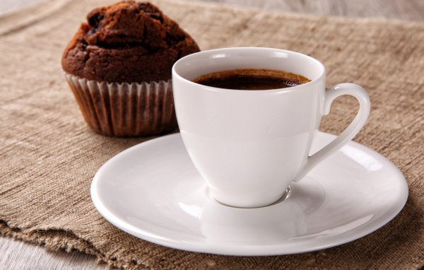 Белая чашка кофе на столе с кексом