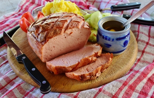 Мясной хлеб на столе с ножом и овощами