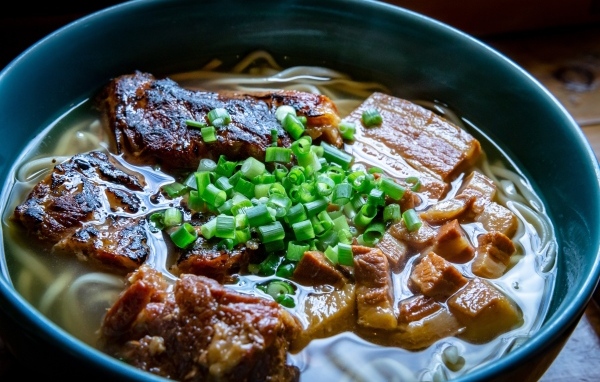 Лапша с мясом и зеленым луком в тарелке