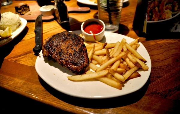 Кусок жареного мяса на тарелке с картофелем фри 