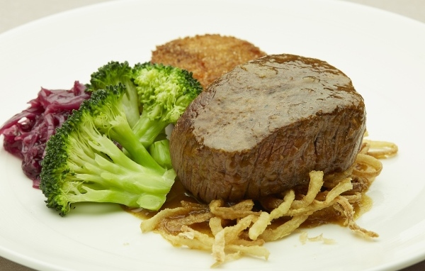 Кусок мяса на тарелке с овощами