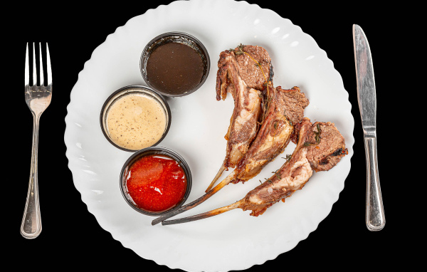 Свиные ребра с соусом на белой тарелке 