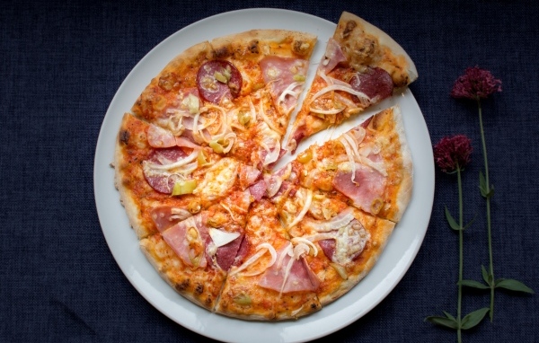 Нарезанная пицца на белой тарелке