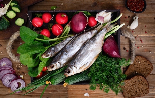 Сушеная рыба на столе с овощами и зеленью 