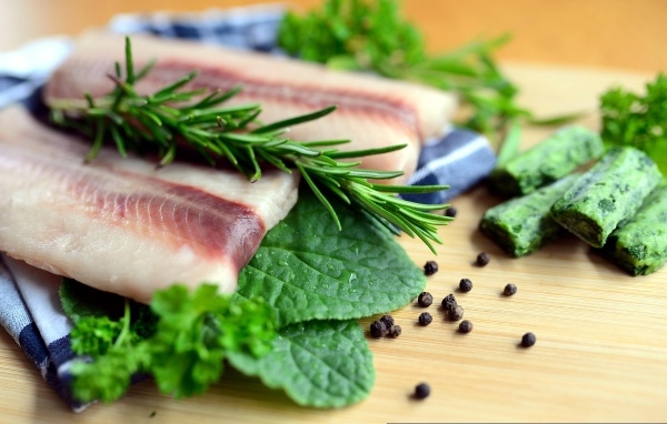 Свежая рыба на доске с зеленью и специями