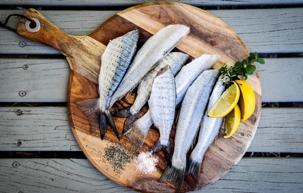 Свежая рыба на доске  с кусочками лимона