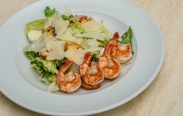 Креветки на тарелке с листьями салата