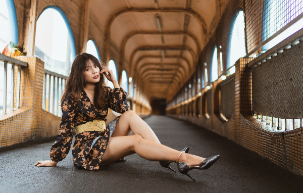 Девушка в красивом коротком платье сидит на полу