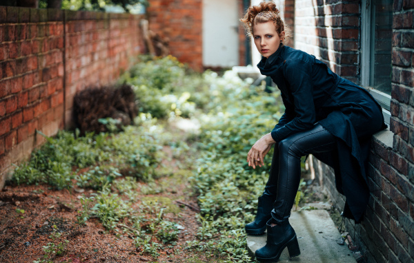 Девушка в черном наряде сидит на окне