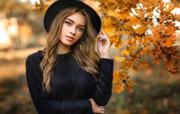 Девушка в черной шляпе стоит у дуба