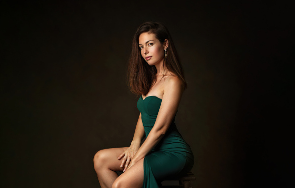 Девушка в зеленом платье сидит на стуле