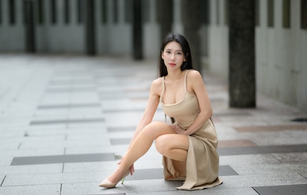 Девушка азиатка в платье сидит на корточках