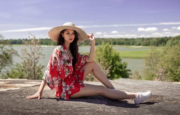 Девушка азиатка в шляпе лежит на камне