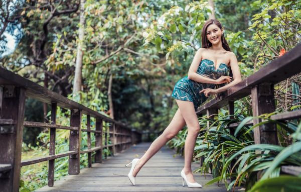 Девушка азиатка в коротком платье у перил на мосту