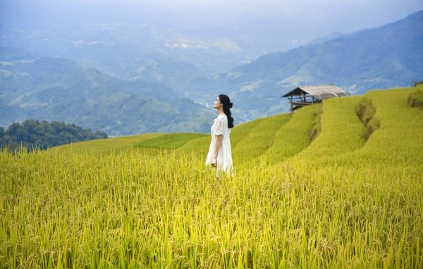 Девушка азиатка в белом платье дышит горным воздухом