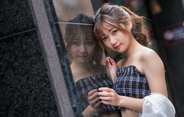 Девушка азиатка отражается в стене