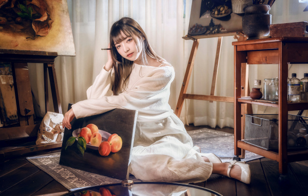 Девушка азиатка сидит с картиной на полу